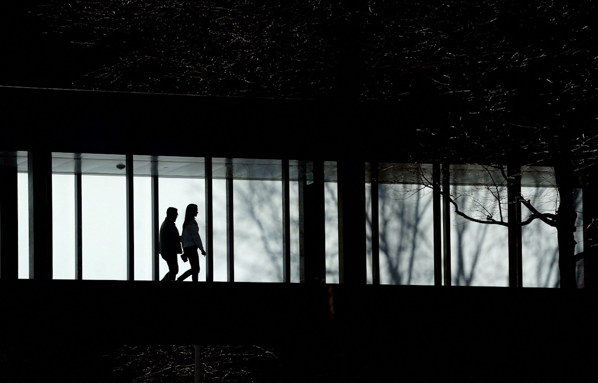 People walk across a skyway linking two office buildings in Tysons Corner, Virginia, U.S., February 9, 2024. REUTERS