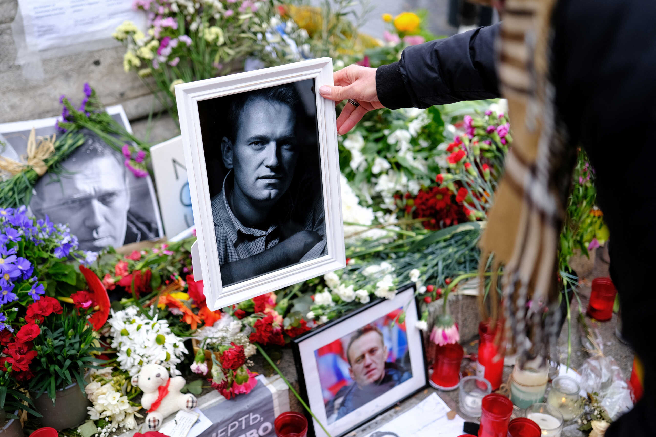 A woman places a portrait of late Russian opposition leader Alexei Navalny, who died unexpectedly in prison ten days ago, on his memorial at Las Ramblas of Barcelona, as people attend a vigil after the body of him, was handed to his mother on Saturday in the Arctic city of Salekhard, in Barcelona, Spain, February 25, 2024. REUTERS