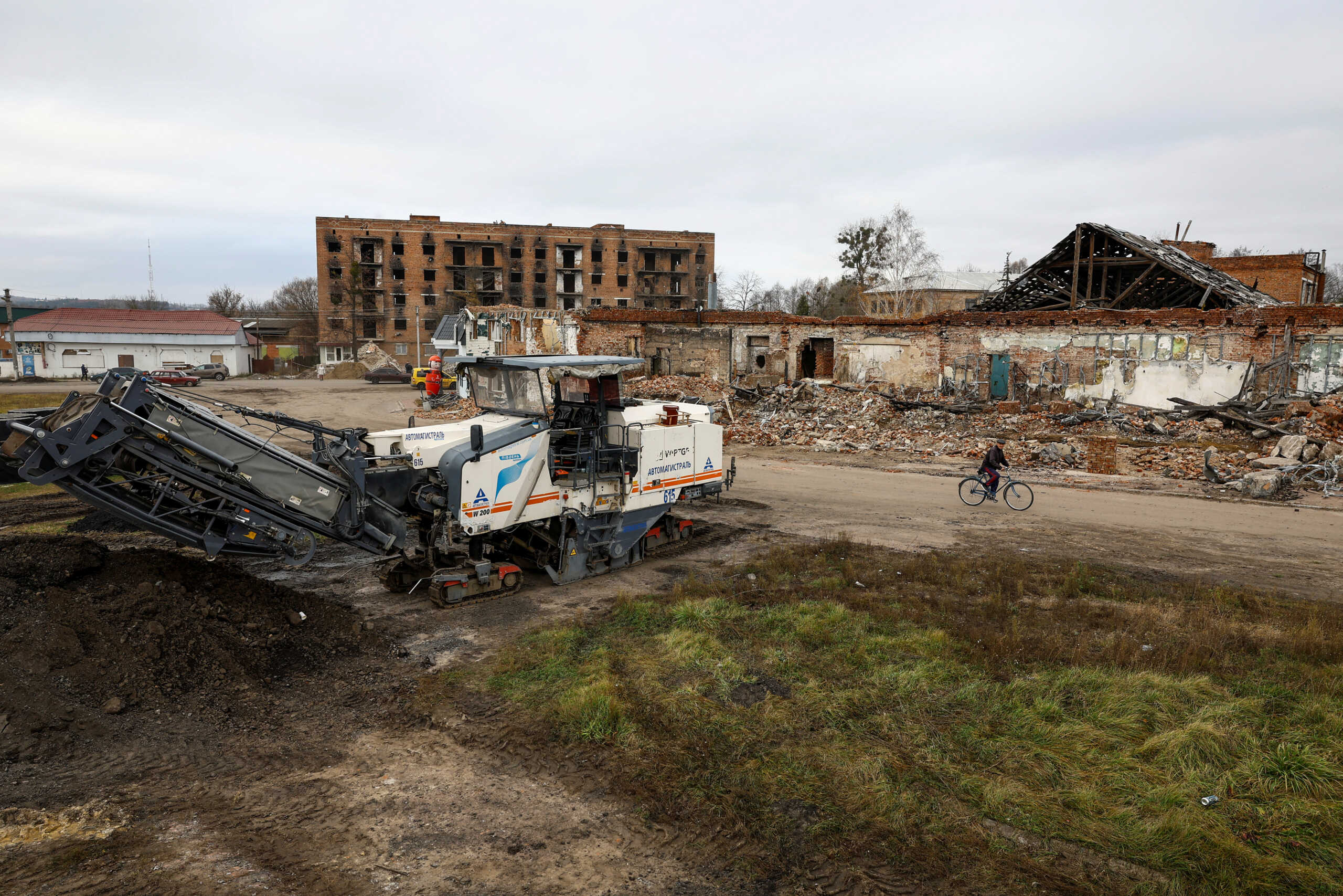 A local man rides on a bicycle past buildings, which were heavily damaged on the first months of Russia's attack on Ukraine in the town of Trostianets, Sumy region, Ukraine November 1, 2023. REUTERS