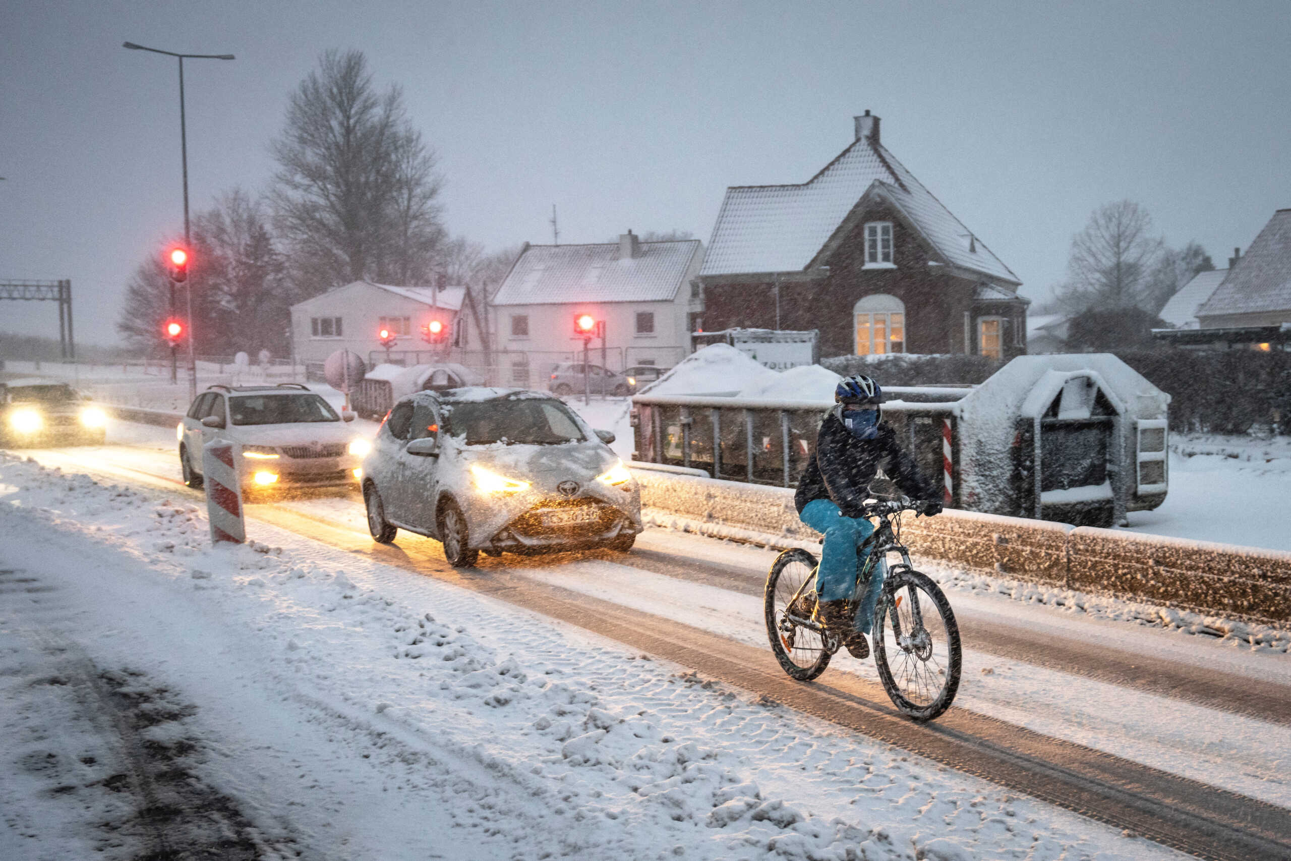 A person rides a bike as cars drive amid snow in Ringsted, Zealand, Denmark, February 9, 2024. Ritzau Scanpix