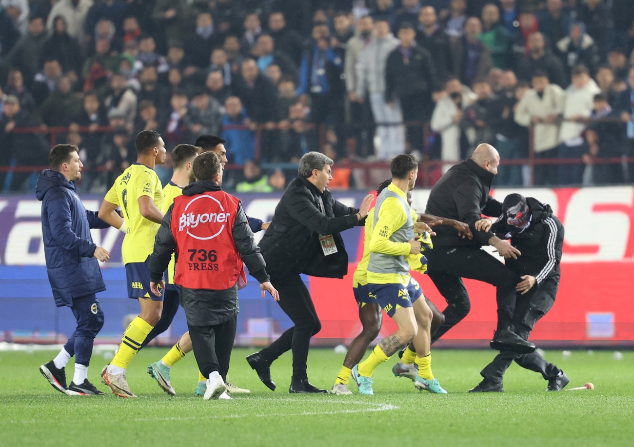 Soccer Football - Super Lig - Trabzonspor v Fenerbahce - Papara Park, Trabzon, Turkey - March 17, 2024   A Trabzonspor fan invades the pitch and clashes with Fenerbahce players and security staff after the match. REUTERS