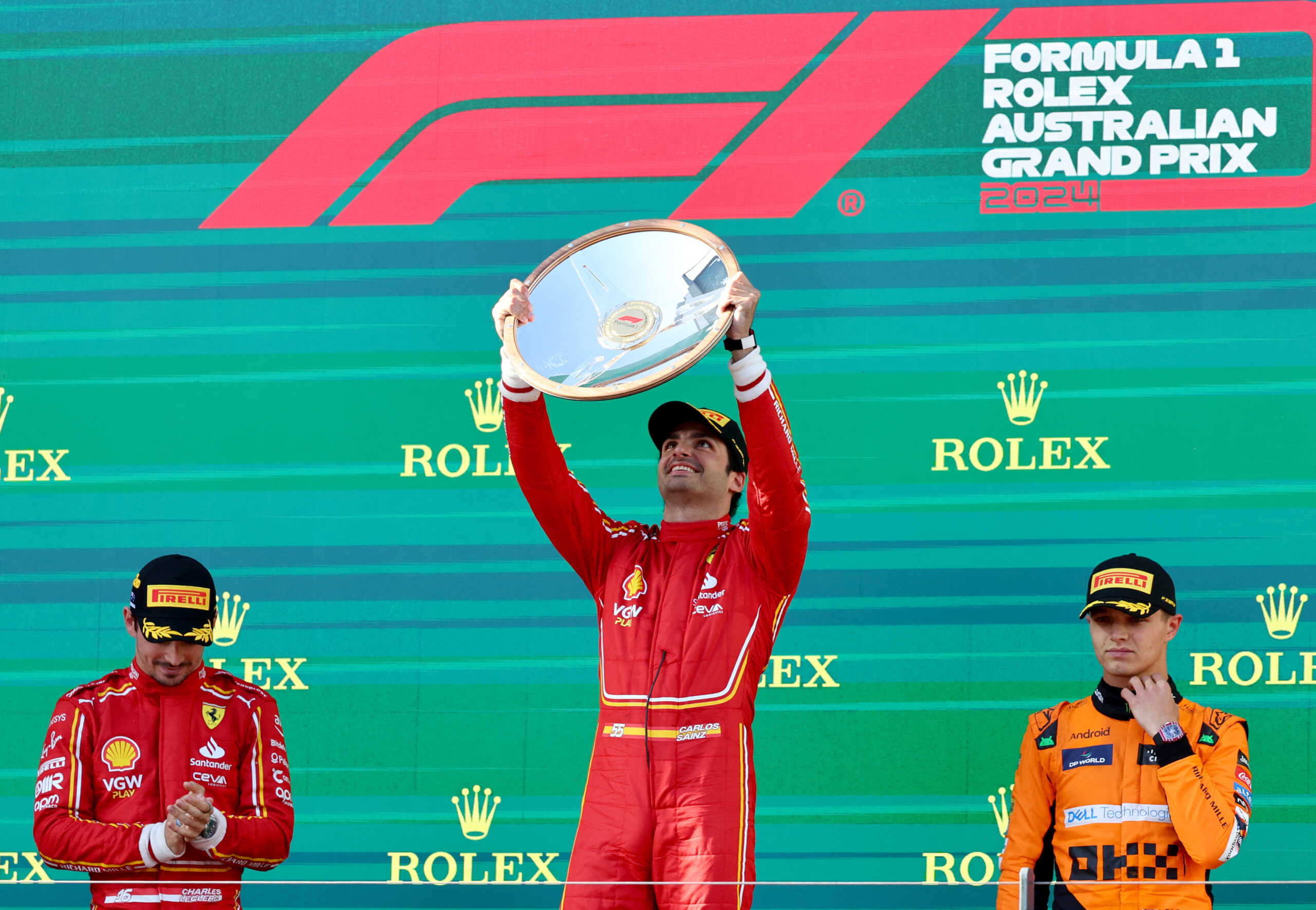 Formula One F1 - Australian Grand Prix - Melbourne Grand Prix Circuit, Melbourne, Australia - March 24, 2024 Ferrari's Carlos Sainz Jr. celebrates with the trophy on the podium after winning the Australian Grand Prix along with second placed Ferrari's Charles Leclerc and third placed McLaren's Lando Norris REUTERS