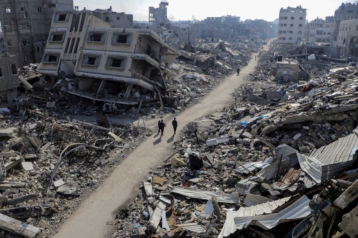 FILE PHOTO: Palestinians walk past destroyed houses, amid the ongoing conflict between Israel and Hamas, in Jabalia refugee camp, in the northern Gaza Strip February 22, 2024. REUTERS