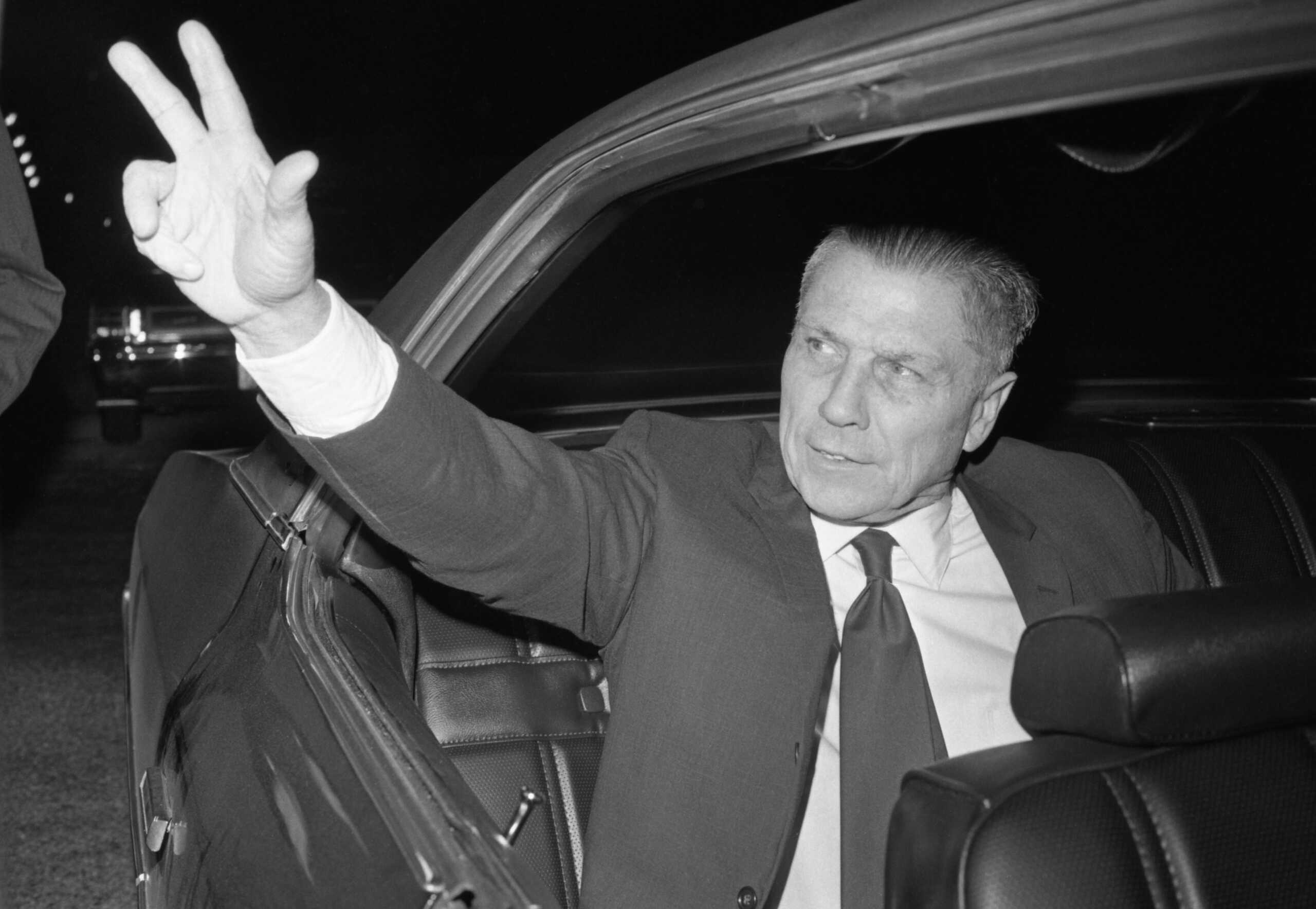 Former Teamster leader James Hoffa waves from the back seat of his car as he leaves the St. Louis airport for a family reunion over Christmas.  Hoffa was released from the federal penitentiary at Lewisburg, PA, and flew to St. Louis to spend Christmas a the suburban home of his daughter and son-in law Mr. and Mrs. Robert Crancer.  (Photo by Bettmann Archive