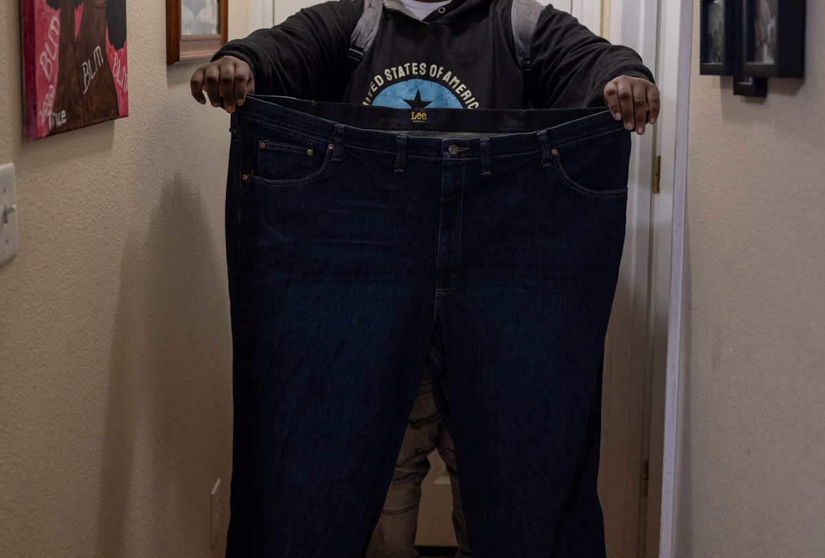 Billy Small III, who is under treatment with Novo Nordisk's weight-loss drug Wegovy, poses with a pair of trousers that he used to wear before starting with the drug treatment, at his home in Oakland, California, U.S., February 5, 2024. REUTERS