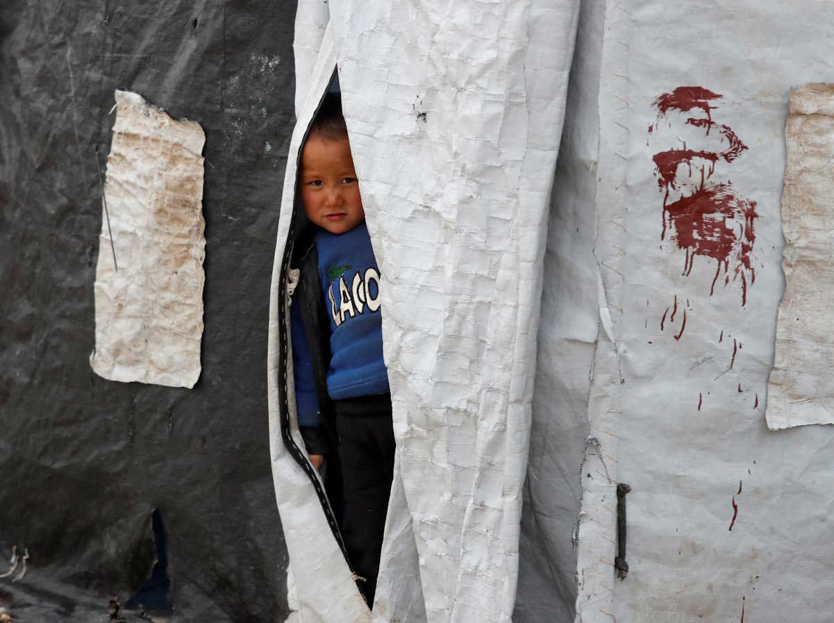 FILE PHOTO: A boy looks out from inside a tent in al-Roj camp, Syria, January 10, 2020. REUTERS