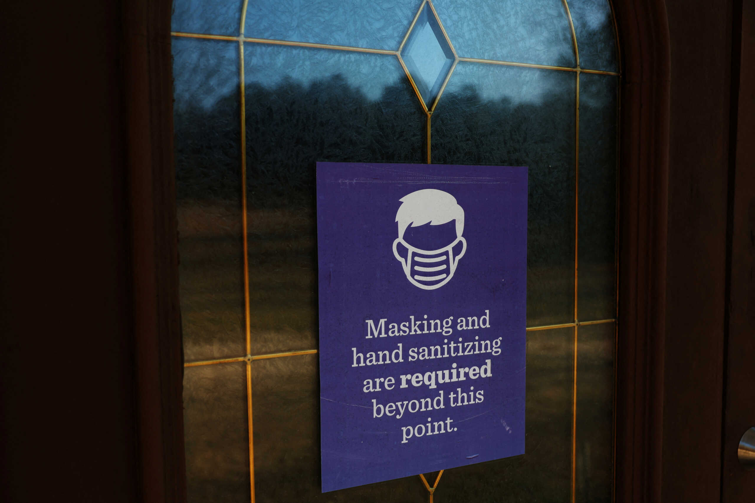 A sign requiring masking and sanitizing hangs at the entrance of a church near Great Falls, South Carolina, U.S., February 2, 2024. REUTERS