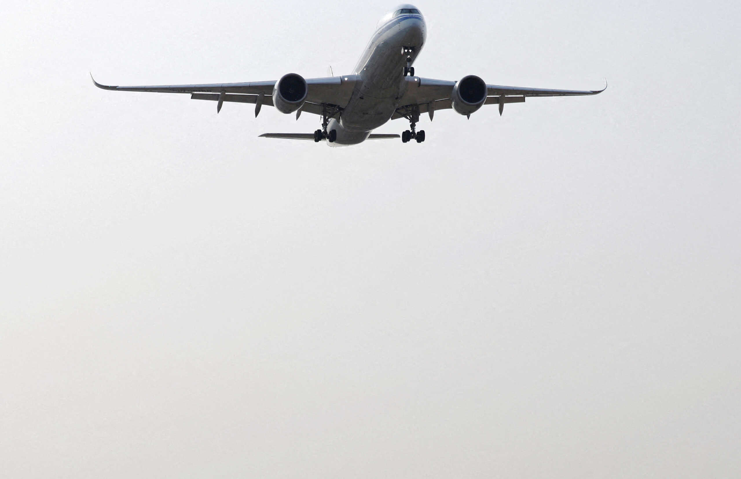 FILE PHOTO: An aircraft flies above visitors at a park near the Beijing Capital International Airport, during the Spring Festival travel rush ahead of the Chinese Lunar New Year, in Beijing, China February 2, 2024. REUTERS