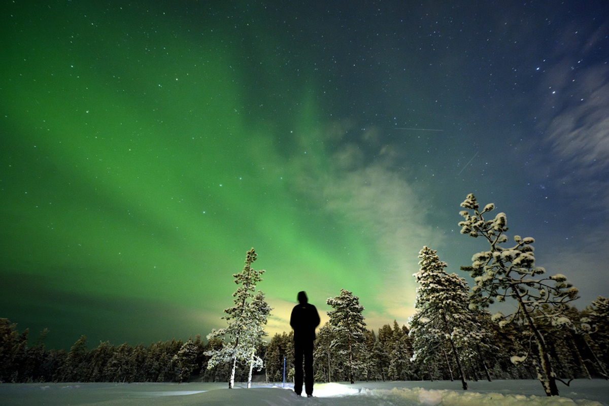 epa11150599 A person watches the northern lights (aurora borealis) illuminate the sky above the village of Akaslompolo in Kolari, beyond the Arctic Circle, Lapland, Finland, 13 February 2024.  EPA