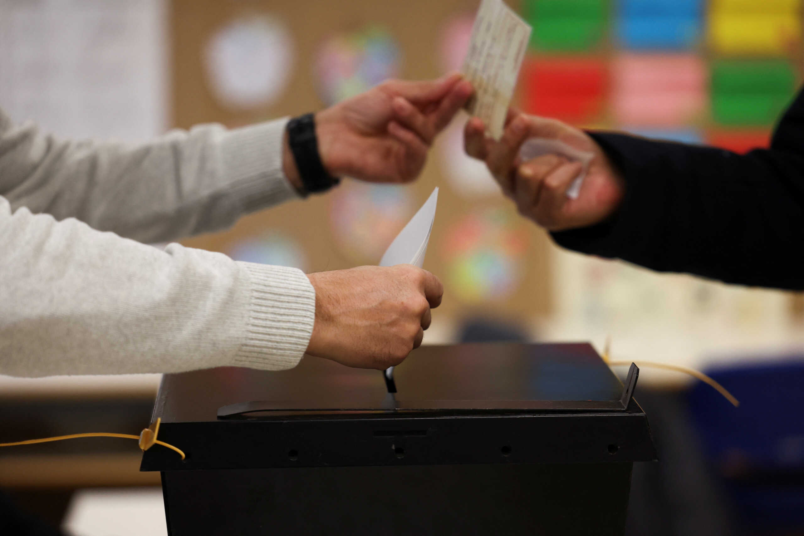 A member of a local electoral commission assists a voter with his ballot, at a polling station during the general election in Espinho, Portugal, March 10, 2024. REUTERS
