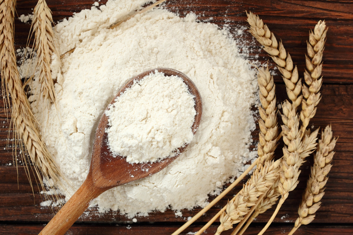 Wooden spoon with wheat flour and wheat ears on plank table. Directly Above.