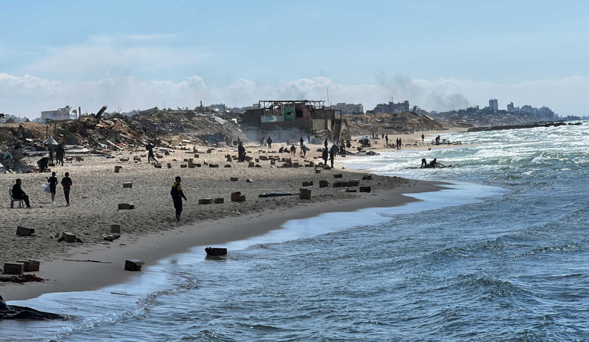 Palestinians gather on a beach as they collect aid airdropped by an airplane, amid the ongoing conflict between Israel and Hamas, in the northern Gaza Strip, March 25, 2024. REUTERS