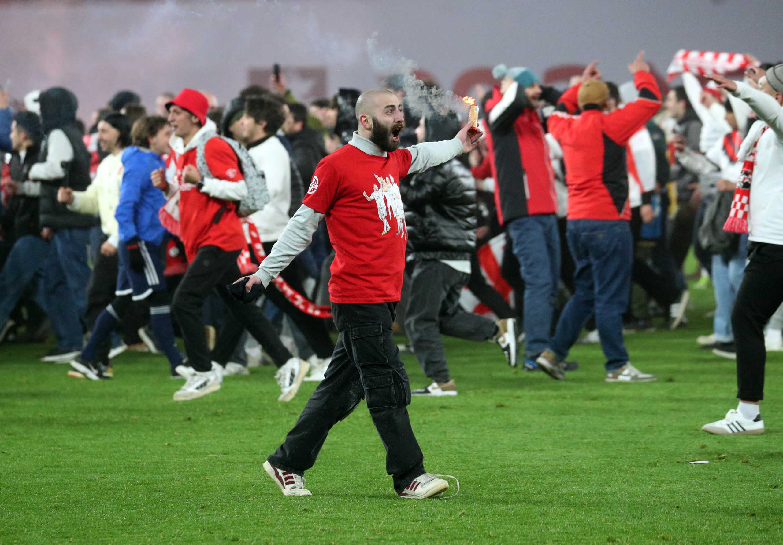 Soccer Football - Euro 2024 Qualifier - Play-off - Georgia v Greece - Boris Paichadze Dinamo Arena, Tbilisi, Georgia - March 26, 2024 A Georgia fan with a flare on the pitch celebrates after qualifying for Euro 2024 REUTERS