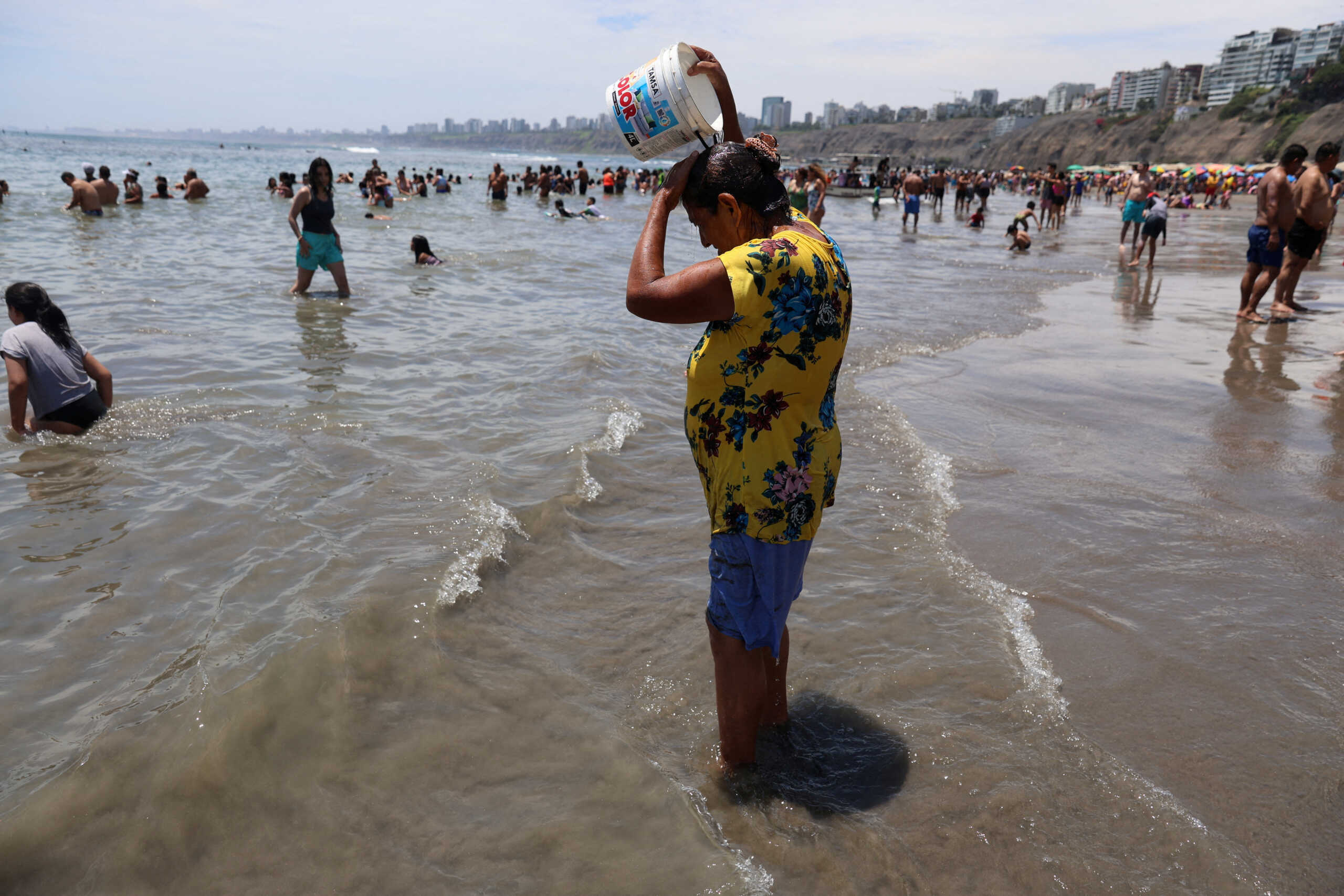 A woman pours water on her head as bathers enjoy a summer day due to the high temperatures at Agua Dulce beach in the Chorrillos district in Lima, Peru, February 25, 2024. REUTERS