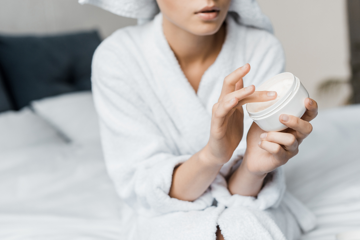 cropped view of woman with cosmetic cream in plastic container