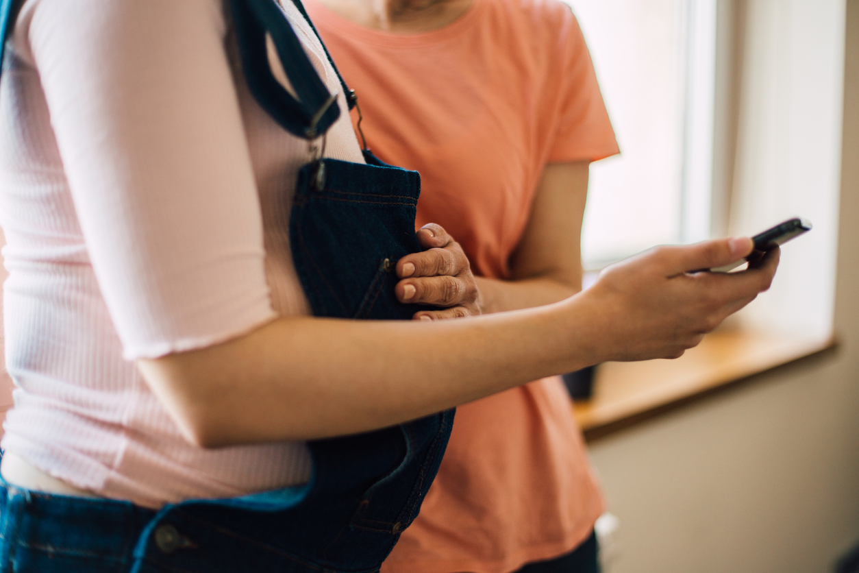 Woman touching pregnancy bump and using mobile phone