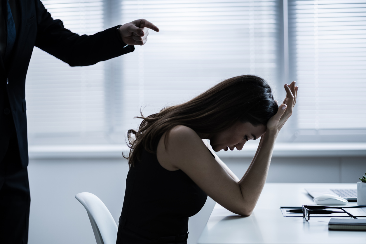 Close-up Of Businessperson Quarreling To Young Businesswoman At Desk