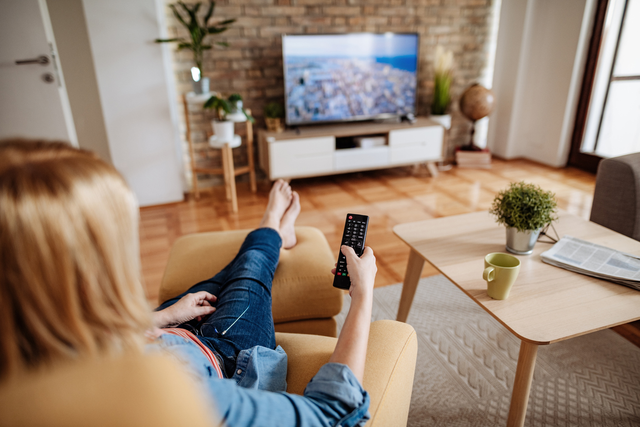 Caucasian blond hair woman, around 60 years old resting at home and watching TV