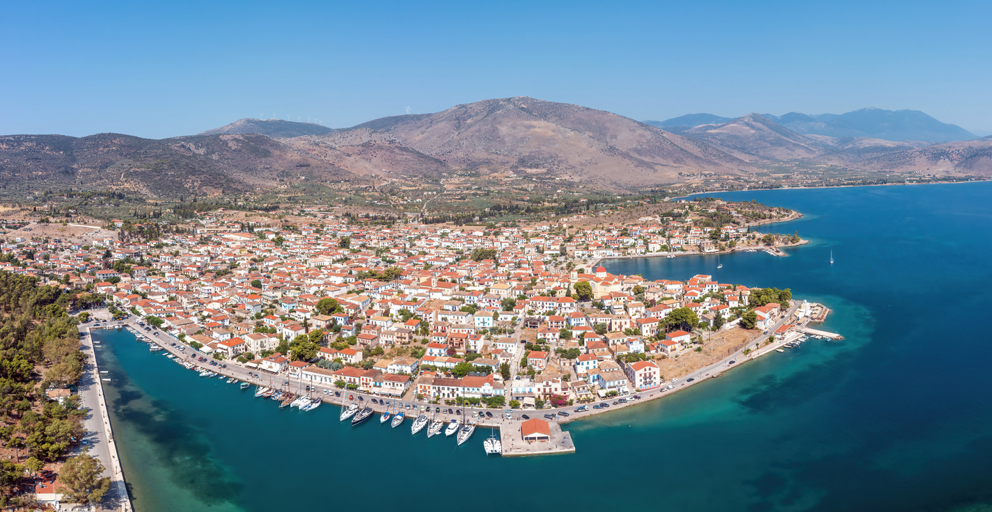 Galaxidi Greece from above, aerial drone view, sunny day. Traditional town in Fokida, waterfront houses and boats, blue sky and sea.
