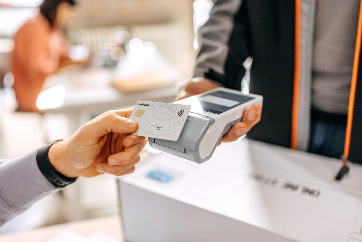 Close up of a man's hand paying delivery with credit card in a office, scanning on a card machine