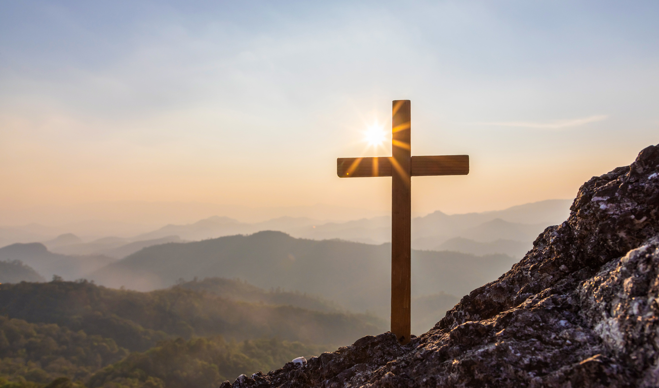 Silhouettes of crucifix symbol on top rock mountain with colorful sunset view background