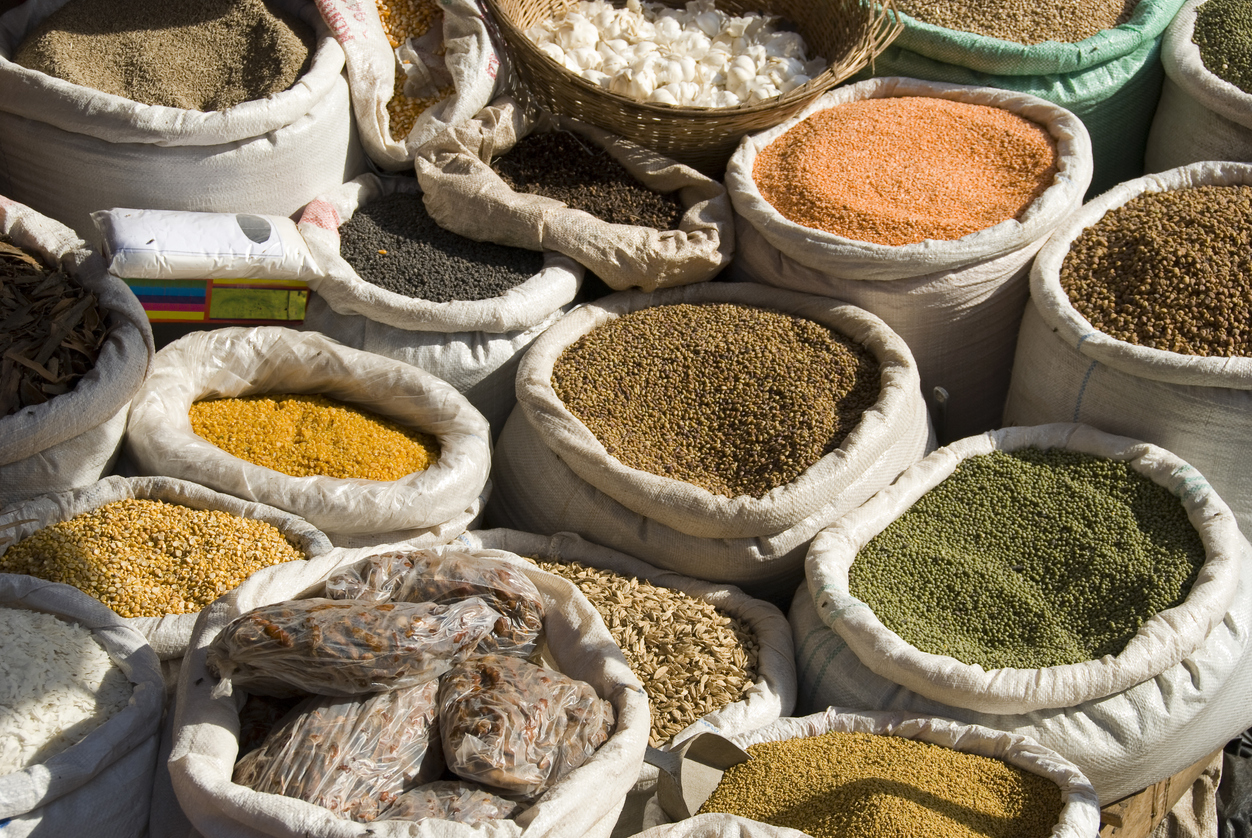 Bags full of spices, dried food herbs and cereals at an african market in Kampala, Africa. The bags stand in the sunlight that makes the colores very bright and vivid.
