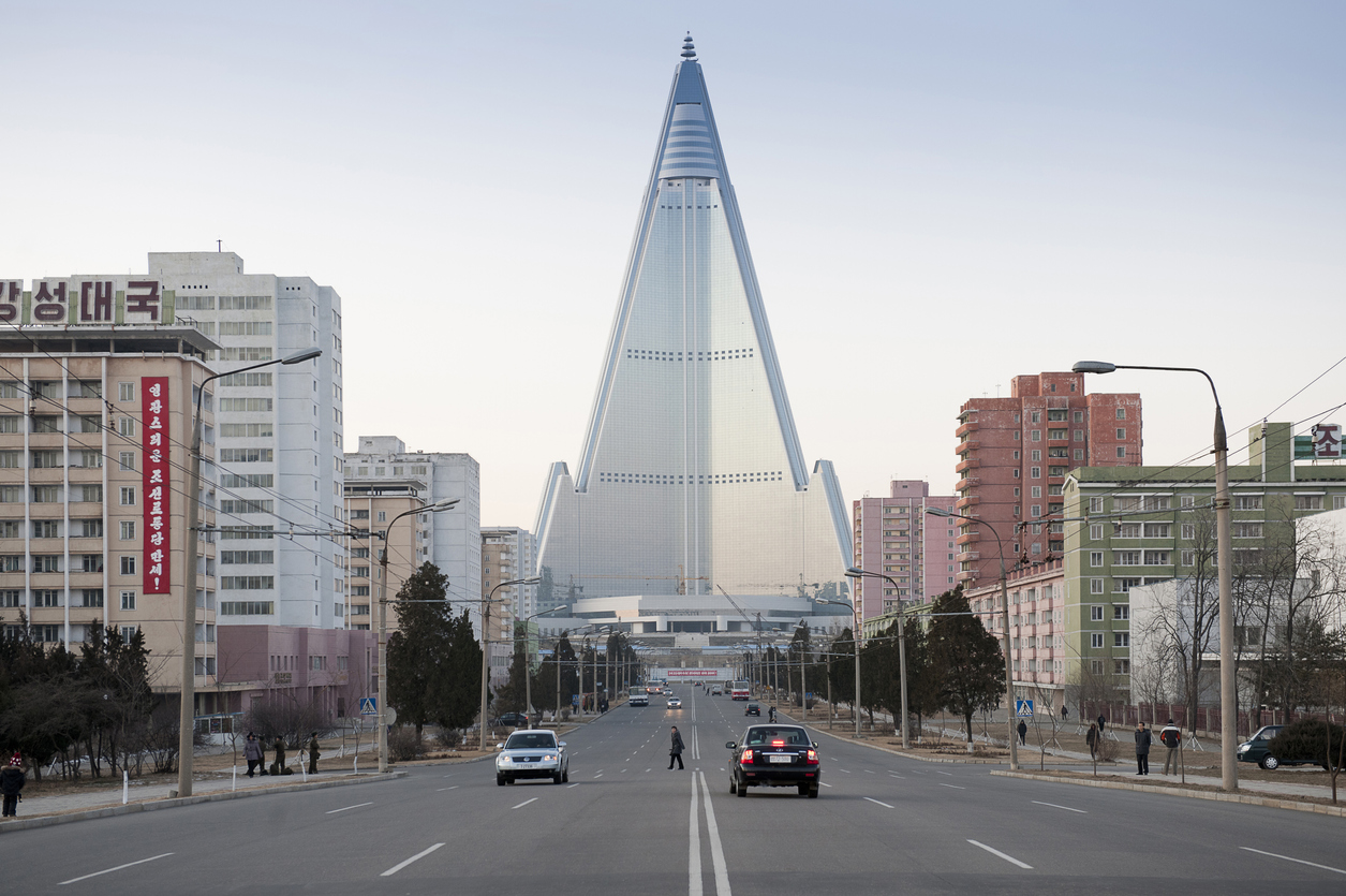 Pyongyang, North Korea, December 16, 2011: City center with skyscraper and traffic. The Ryugyong hotel was many years unfinished. A foreign company covered the facade with glass and now it looks not like a ruin any more. Inside it is still empty.