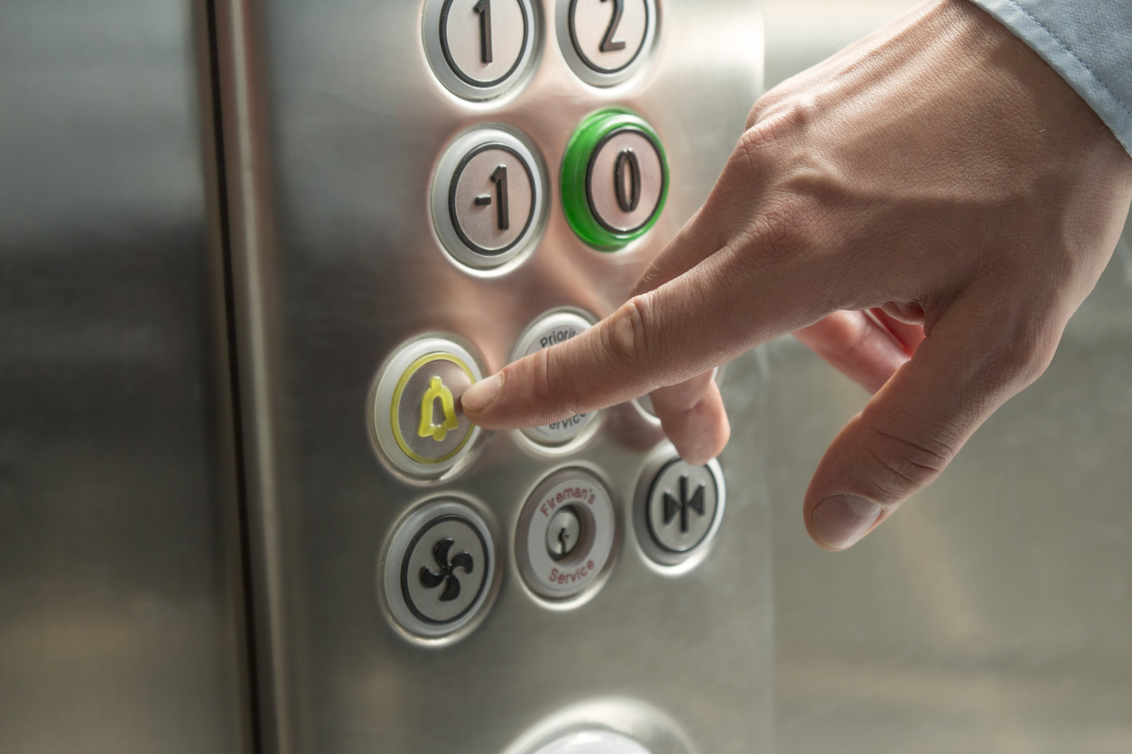 Hand pressing the alarm button in the elevator
