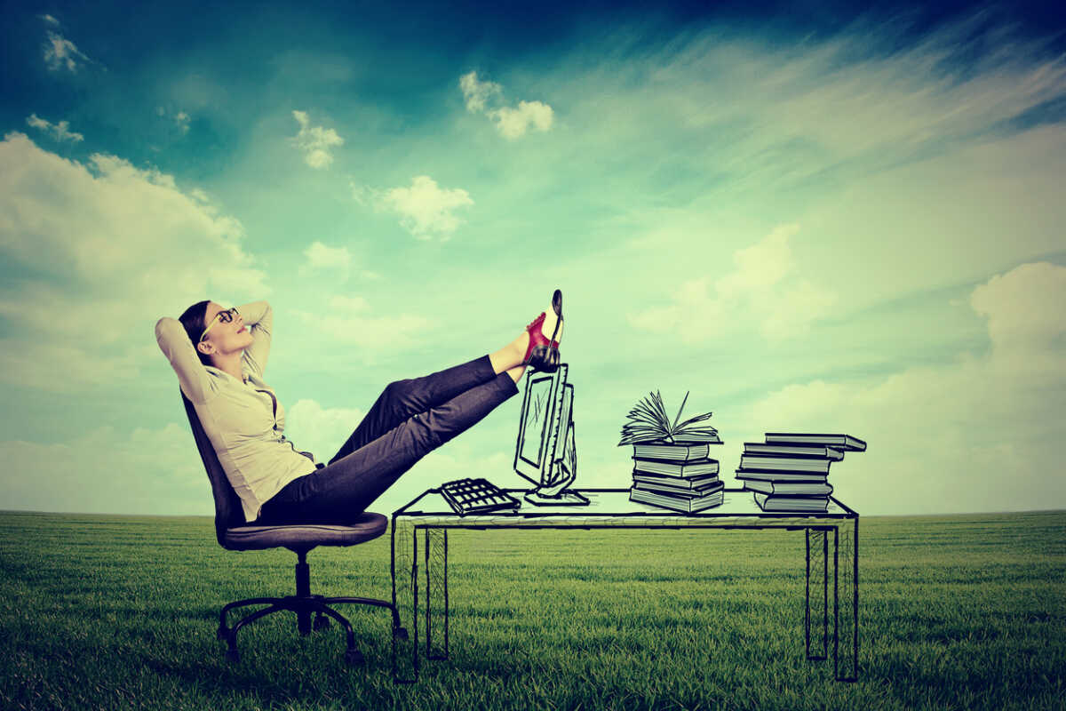 young businesswoman relaxing sitting in the office in the middle of a green meadow. Stress free working environment concept. Daydreaming entrepreneur