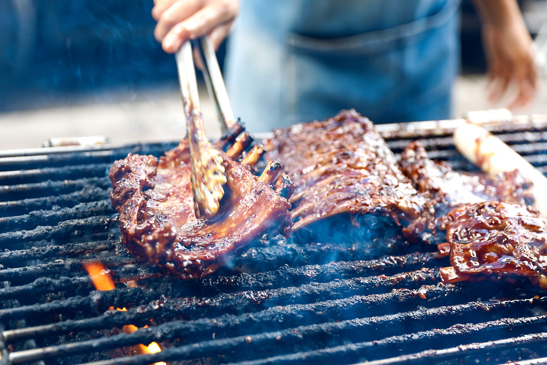 Barbecue pork ribs-grilled. A close up photo of a chef hands grilled a barbeque pork ribs. The chef holding the ribs with a tongs. For more pictures like this https: