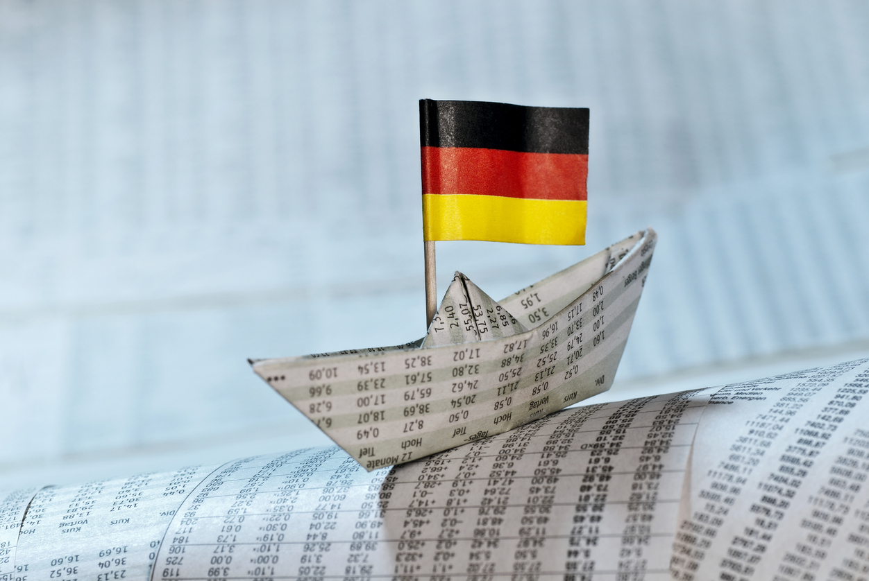 Paper ship with German flag on newspaper pages with course tables.