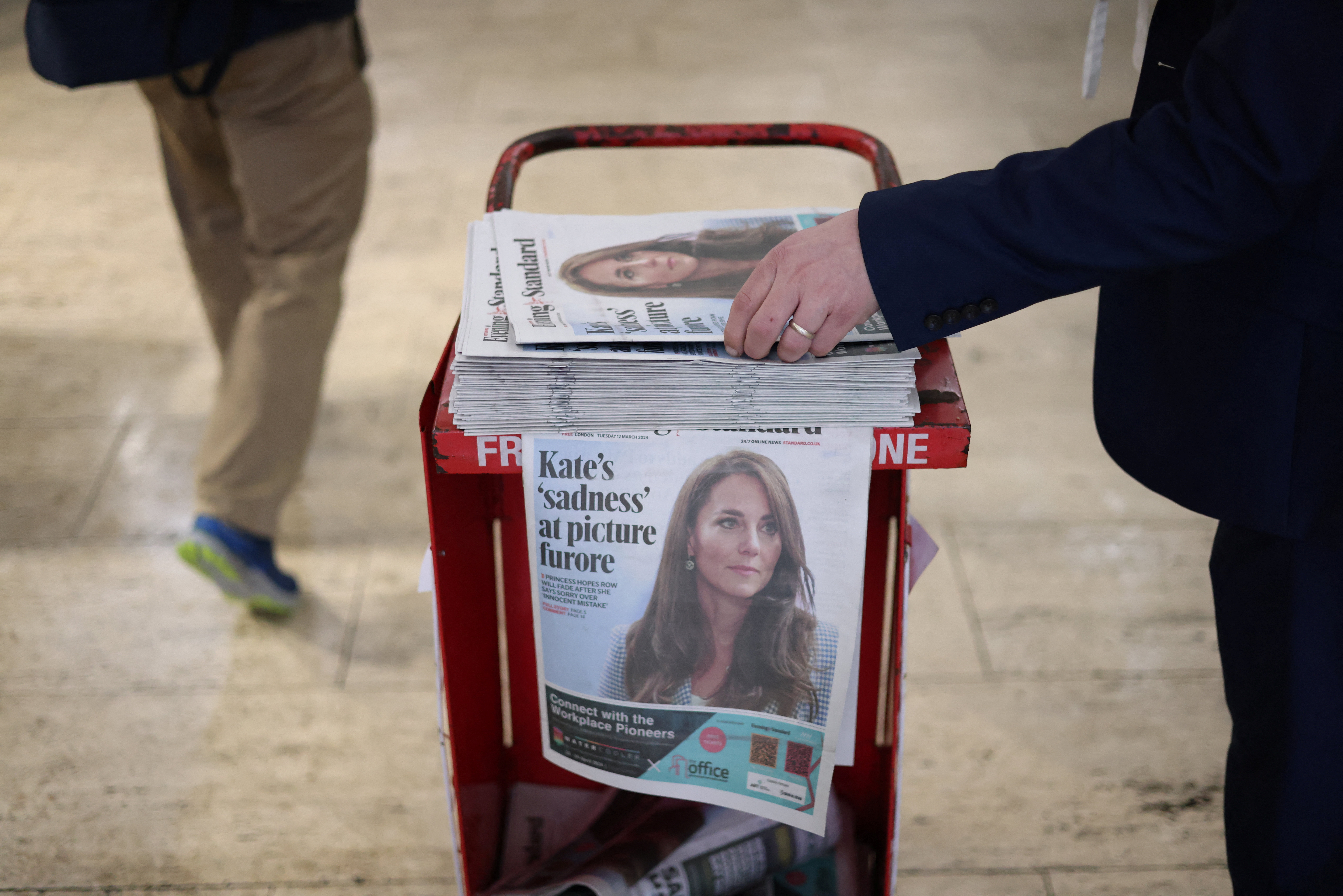 A commuter picks up a copy of the Evening Standard featuring a picture of Britain's Catherine, Princess of Wales, on the front page at subway station in London, Britain, March 12, 2024. REUTERS