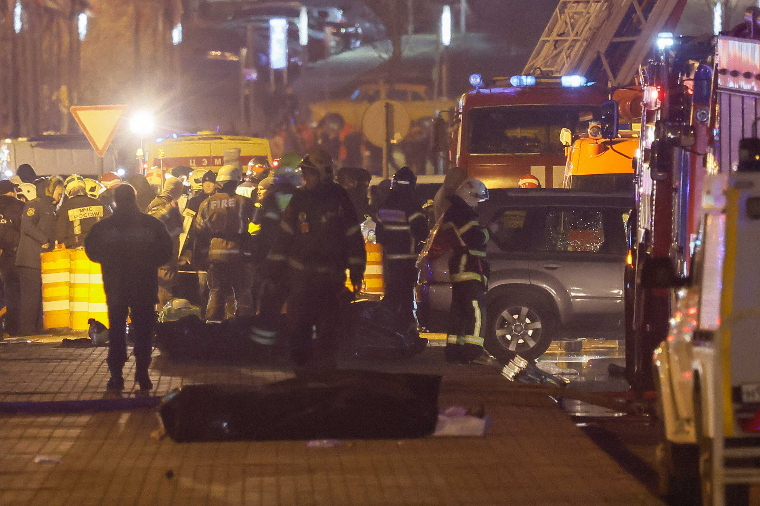 Specialists gather near the covered bodies of killed people near the Crocus City Hall concert venue following a shooting incident, outside Moscow, Russia, March 23, 2024. REUTERS