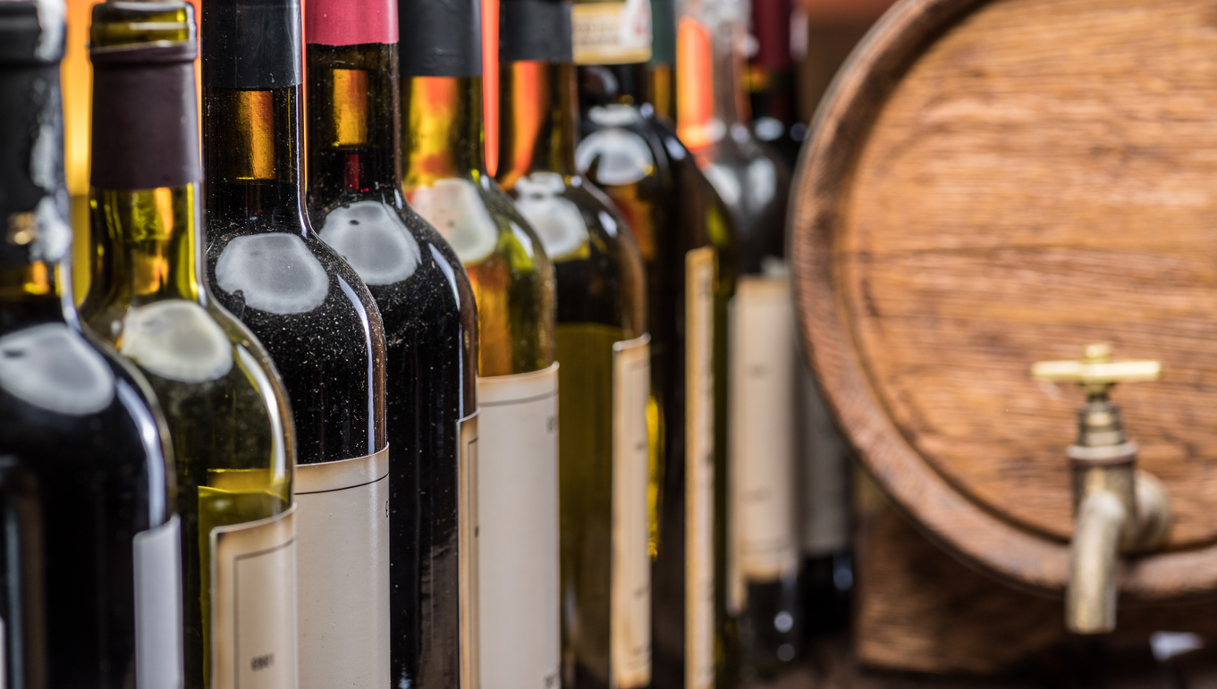Wine bottles in row and oak wine keg.