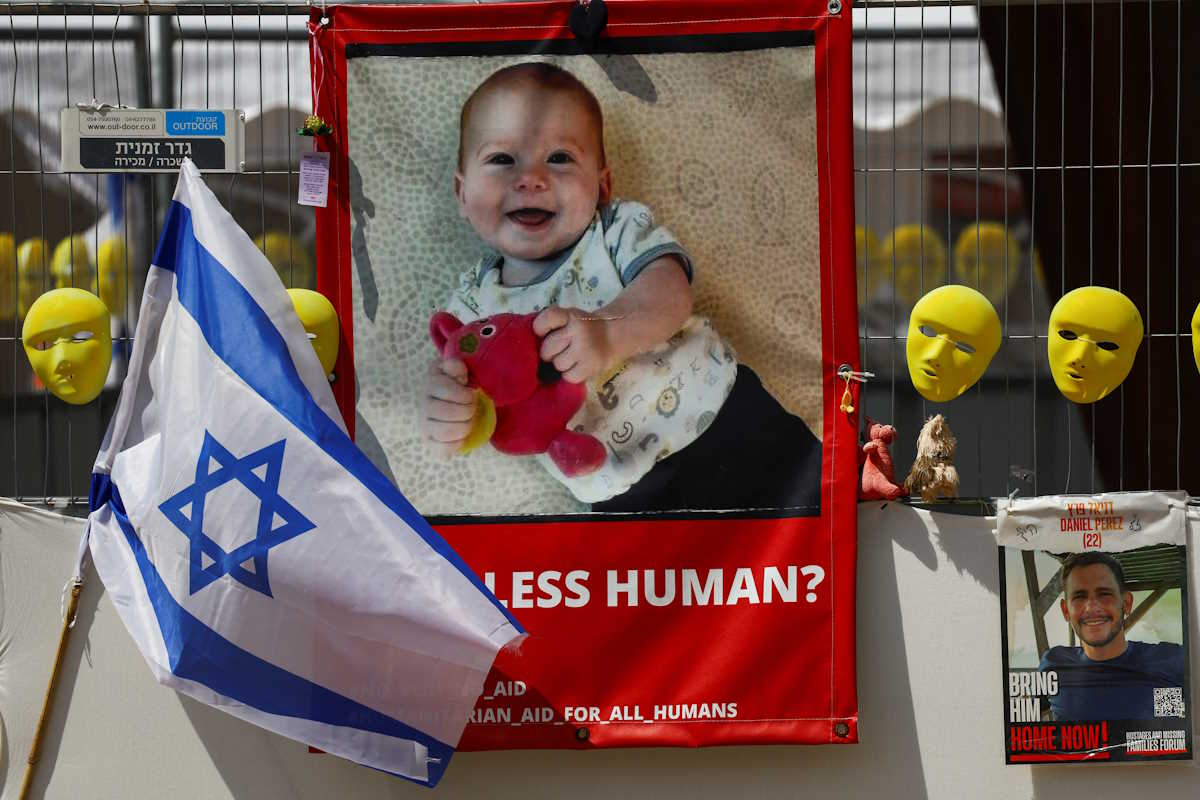 An Israeli flag is seen next to posters with images of a child and a man, hostages kidnapped in the deadly October 7 attack on Israel by the Palestinian Islamist group Hamas from Gaza, as the conflict between Israel and Hamas continues, in Tel Aviv, Israel, April 10, 2024. REUTERS