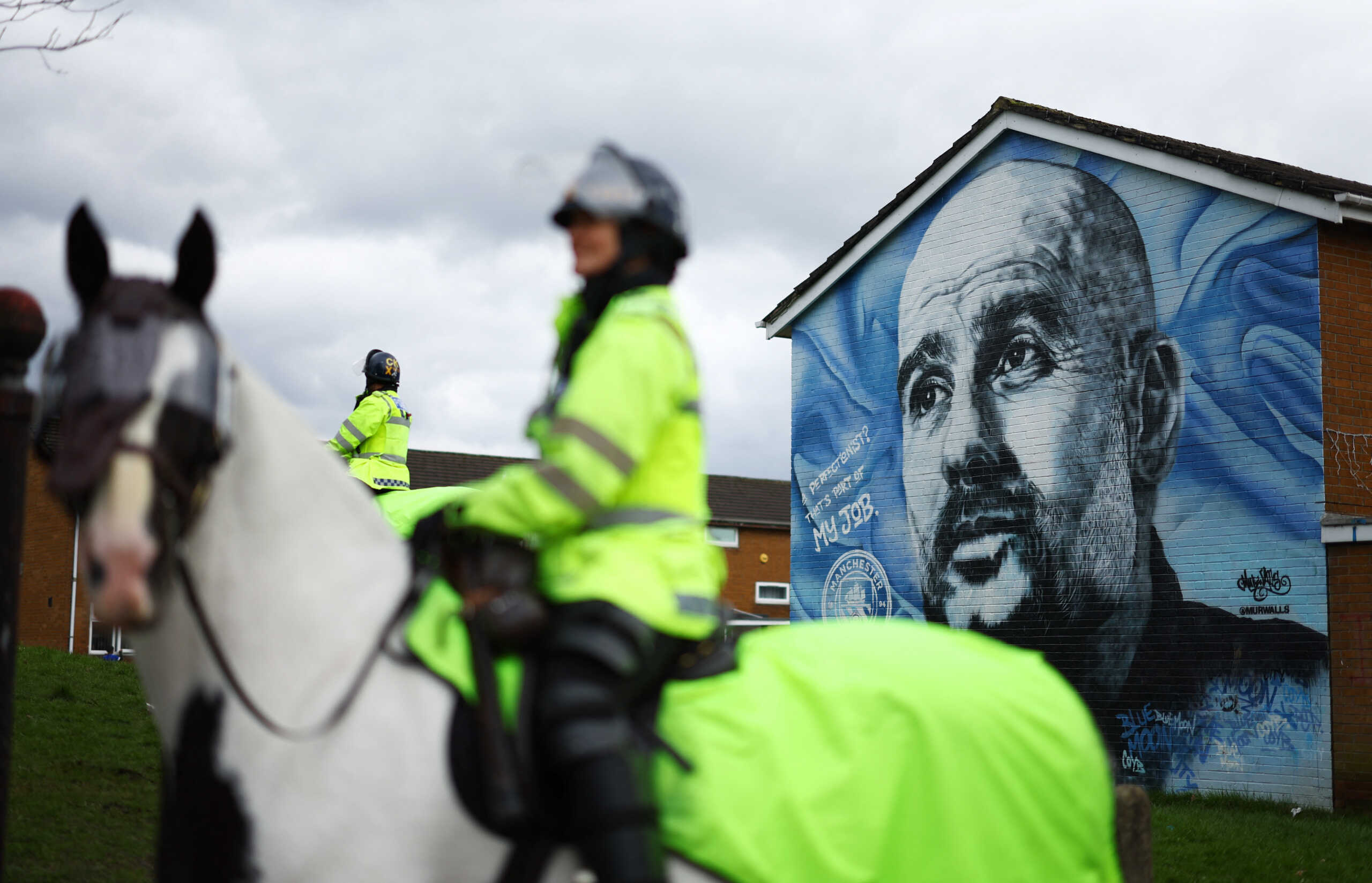 Soccer Football - Premier League - Manchester City v Manchester United - Etihad Stadium, Manchester, Britain - March 3, 2024 Police are seen by a mural of Manchester City manager Pep Guardiola outside the stadium before the match Action Images via Reuters