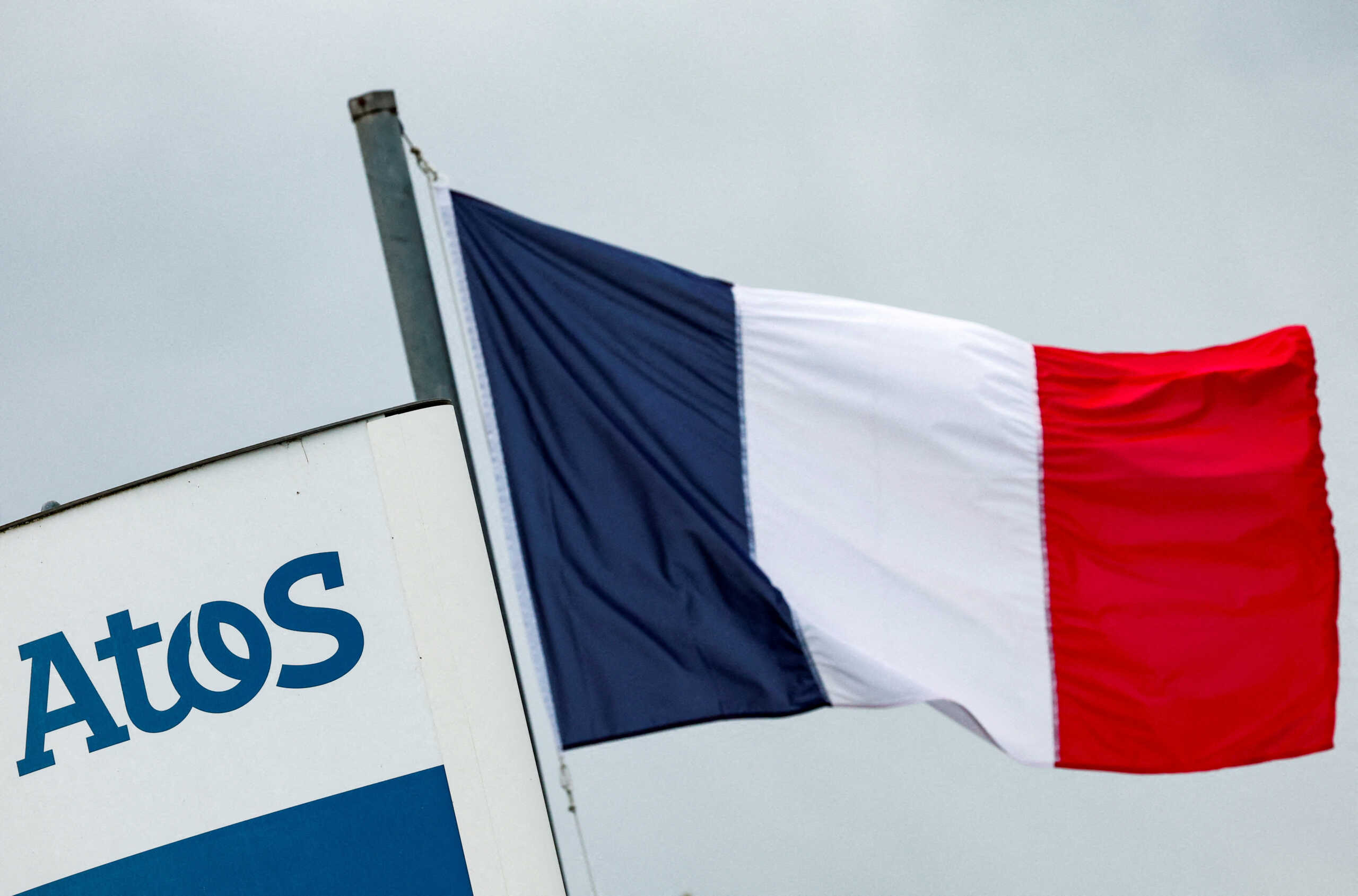FILE PHOTO: A French national flag flies near a logo of French IT consulting firm Atos, at the entrance of a company's building, in Angers, France, March 20, 2024. REUTERS
