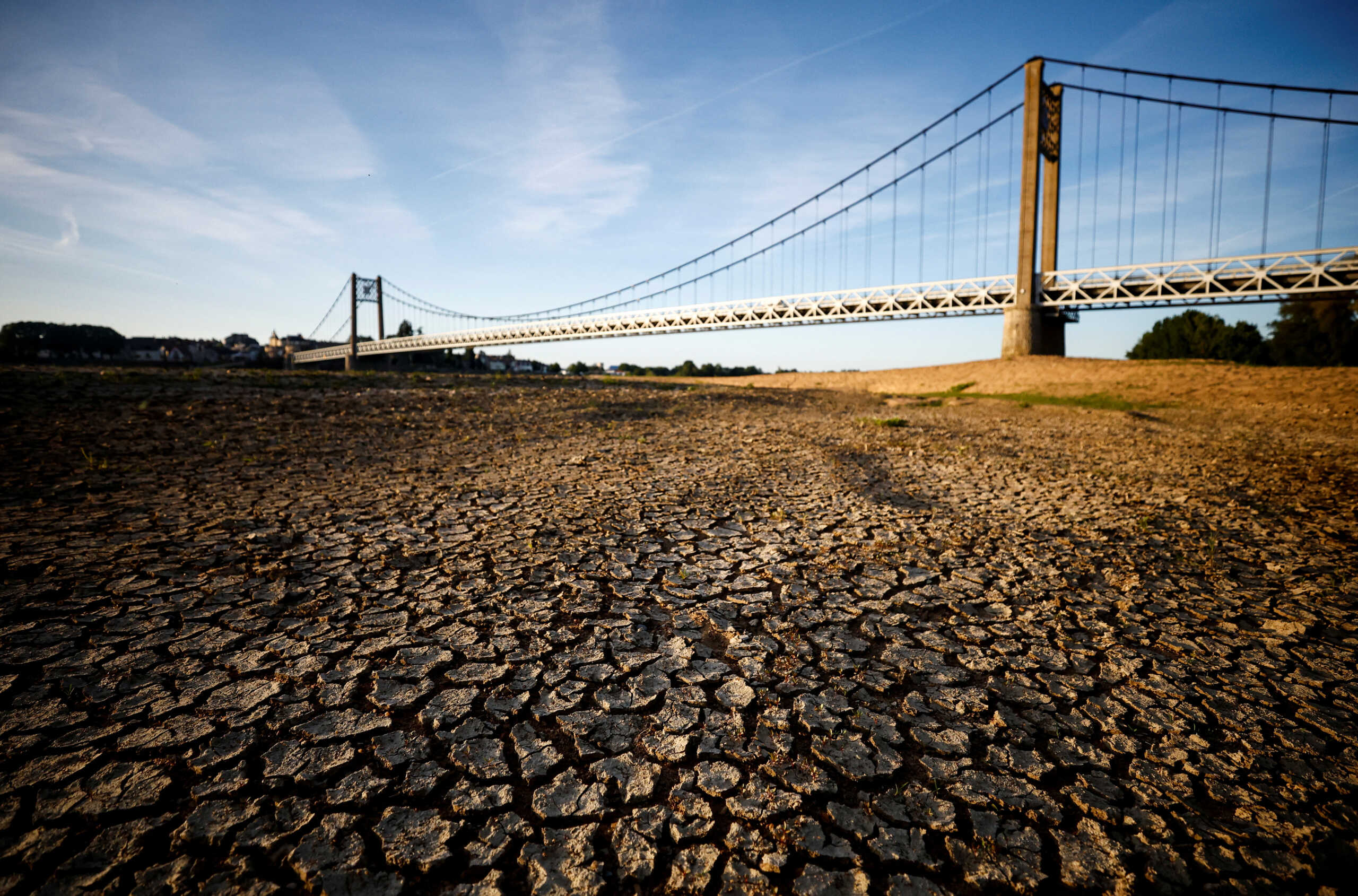 FILE PHOTO: Cracked and dry earth is seen in the wide riverbed of the Loire River near the Anjou-Bretagne bridge as a heatwave hits Europe, in Ancenis-Saint-Gereon, France, June 13, 2022. REUTERS