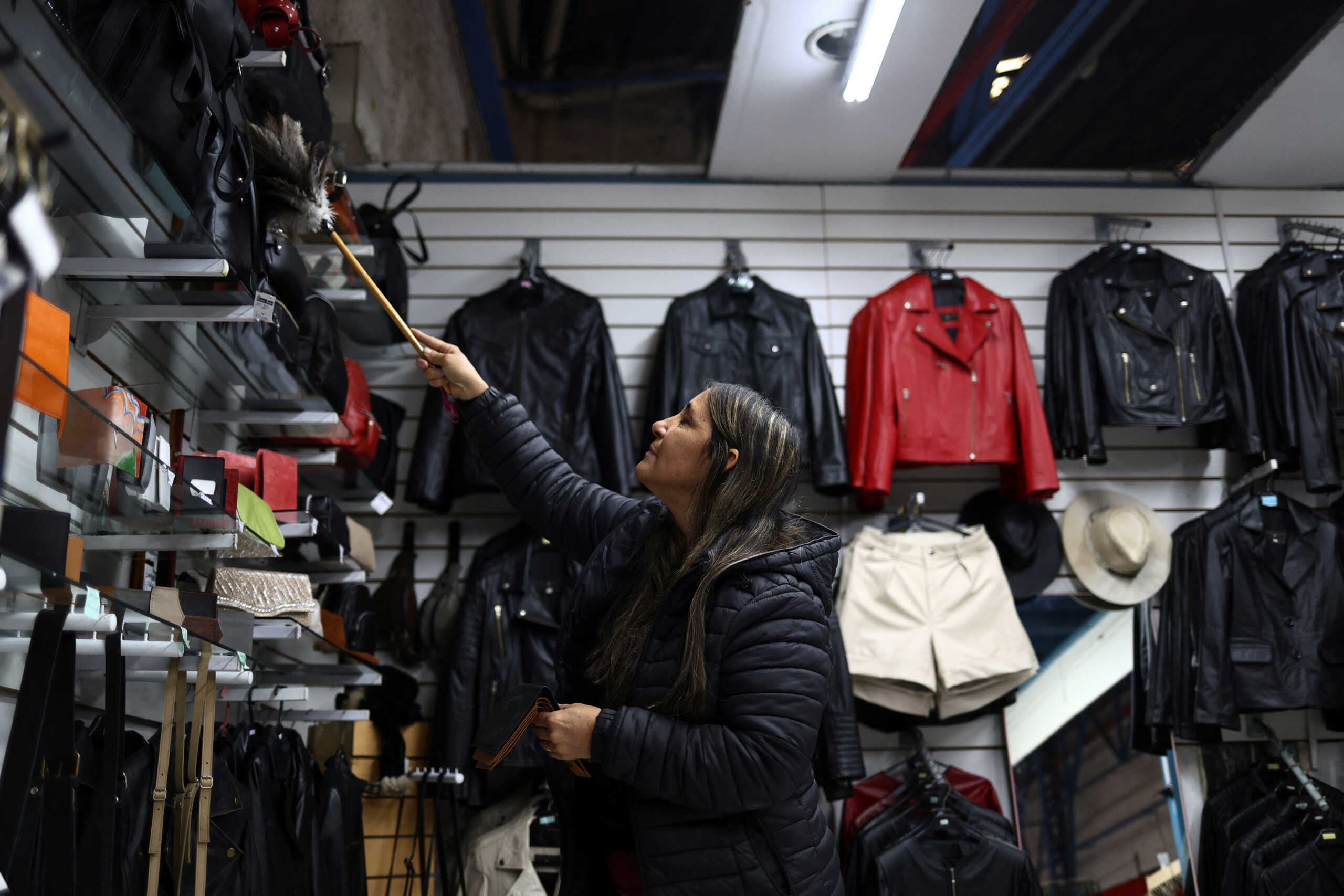 A woman cleans with a duster at a clothing store, as Argentina is battling inflation that is running on an annual basis above 275%, in Buenos Aires, Argentina, April 11, 2024. REUTERS