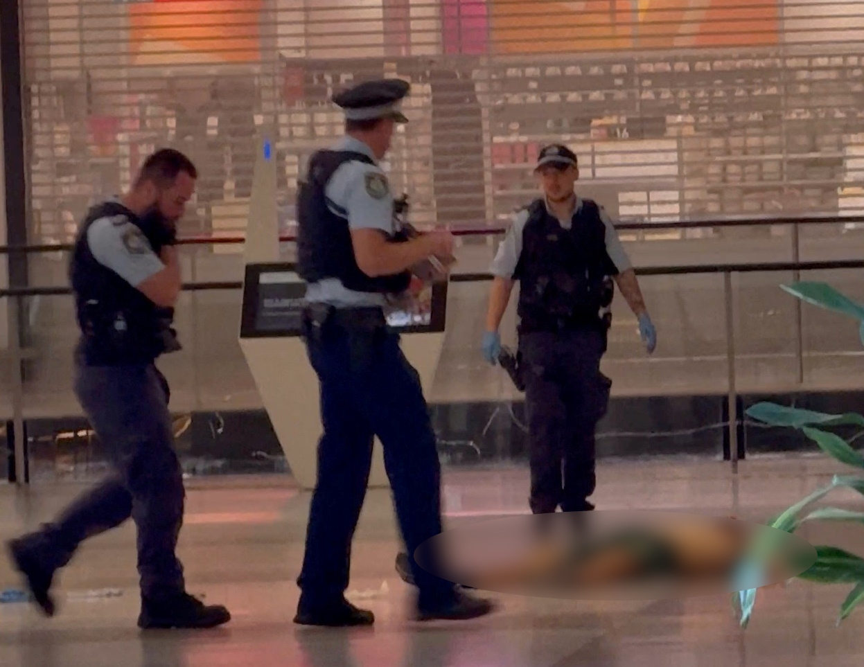 SENSITIVE MATERIAL. THIS IMAGE MAY OFFEND OR DISTURB  Police officers walk next to the body of an attacker, who was shot after fatally wounding several people with a knife, in Westfield Bondi Junction shopping center, in Sydney, Australia April 13, 2024 in this screengrab obtained from a social media video. Glaucia Manao