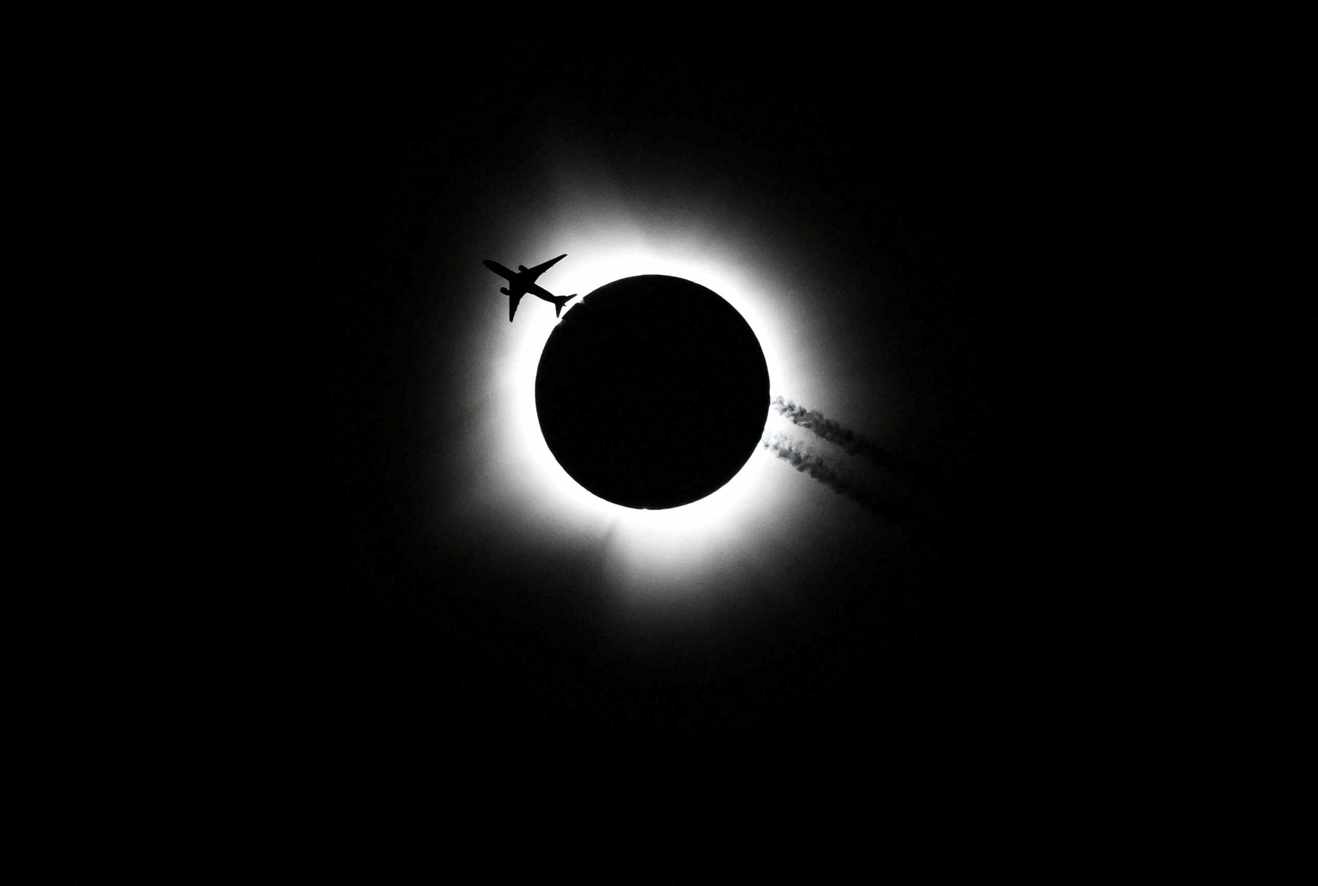 An airplane passes near the total solar eclipse during the Hoosier Cosmic Celebration at Memorial Stadium in Bloomington, Indiana, U.S. April 8, 2024. Bobby Goddin