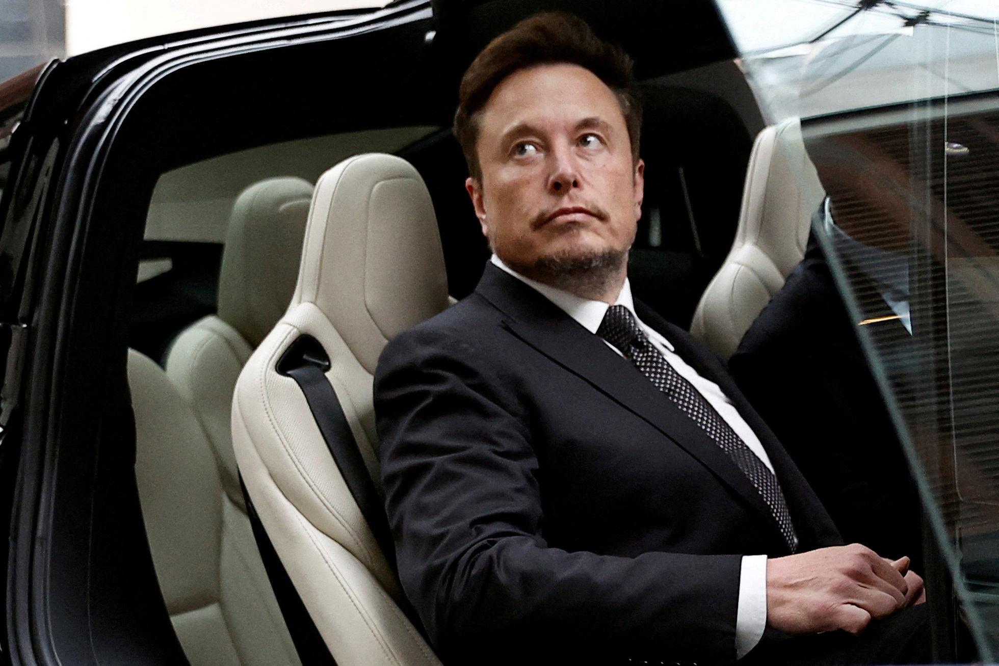 FILE PHOTO: Tesla Chief Executive Officer Elon Musk gets in a Tesla car as he leaves a hotel in Beijing, China May 31, 2023. REUTERS