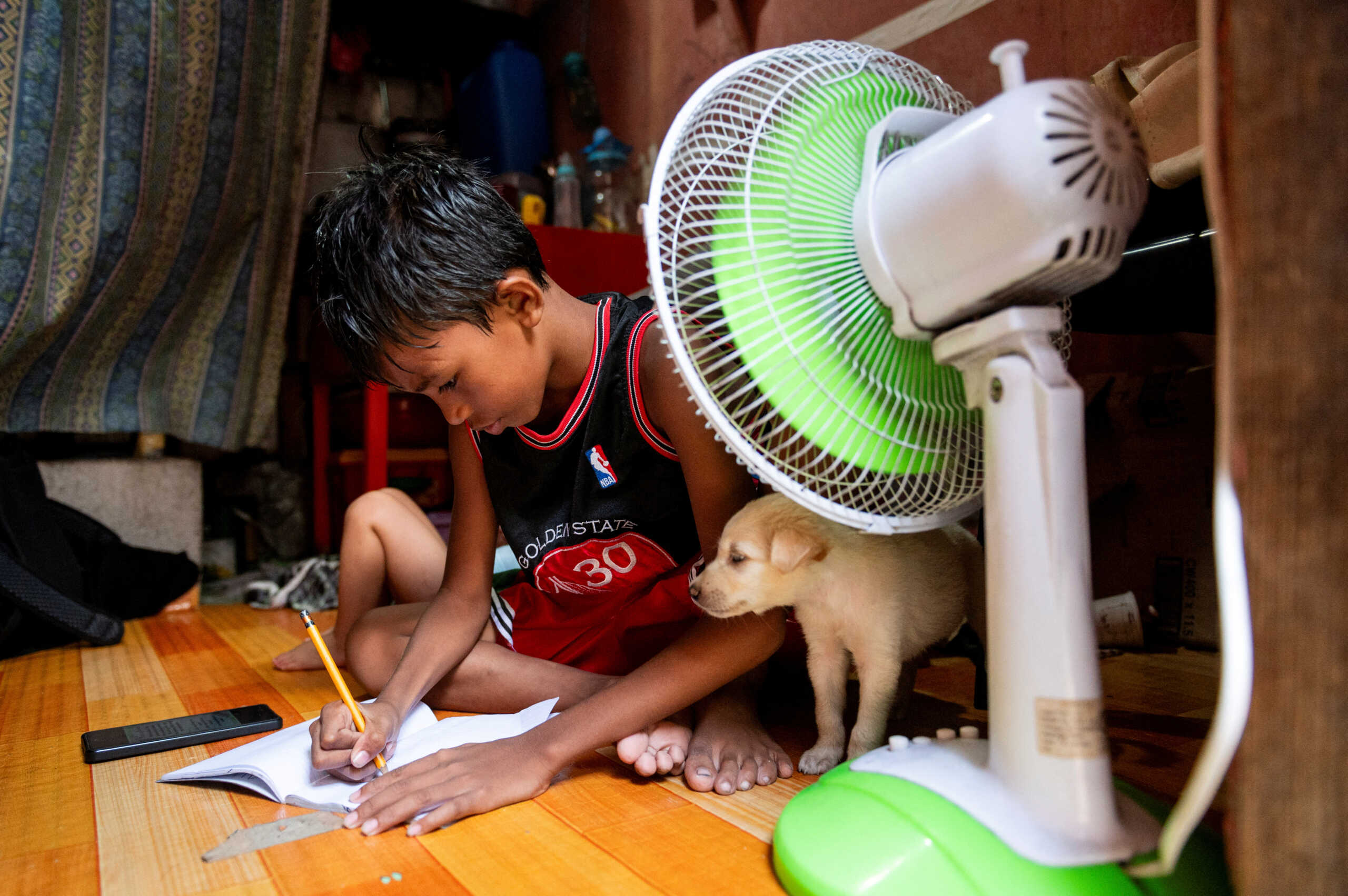 A student answers his learning module following the suspension of in-person classes, inside his house in Manila, Philippines, April 26, 2024. REUTERS