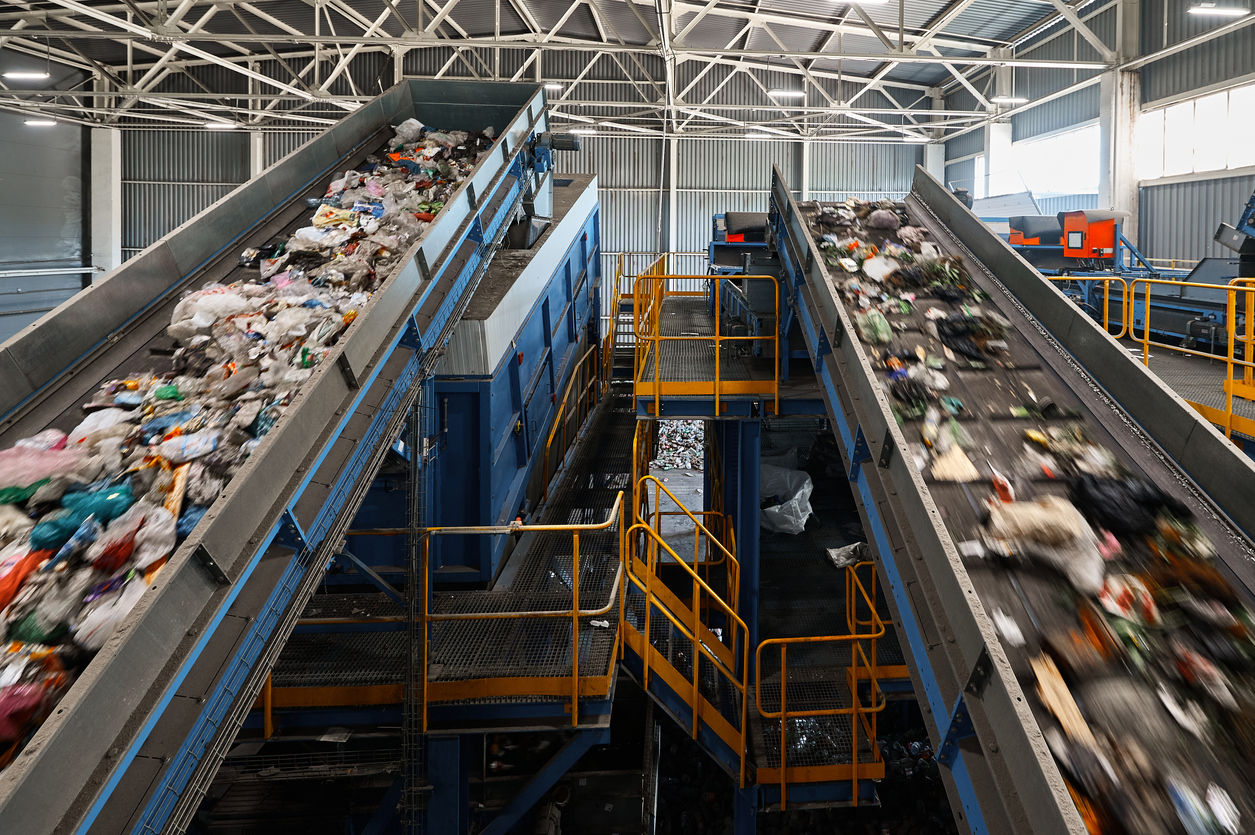 Conveyors carry trash and empty platforms for workers control at waste recycling plant. Utilization of waste materials. Sustainable production principles