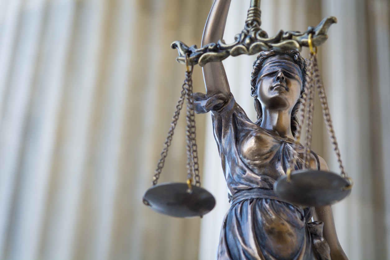 The statue of justice Themis or Justitia, the blindfolded goddess of justice against ionic order colonnade, with copy space