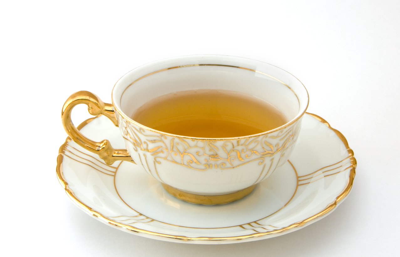 Tea served in a beautiful china cup and saucer with gold leaf pattern.
