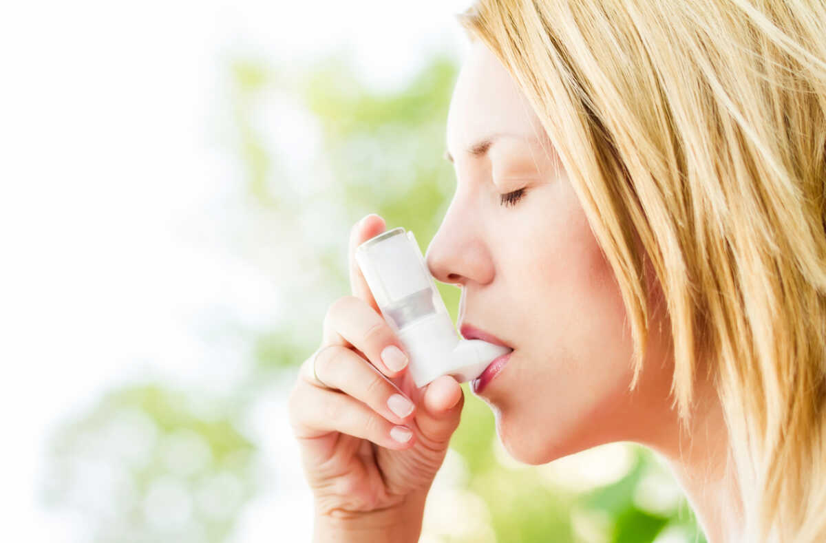 Girl is using metered dose inhaler to relieve asthma symptoms.