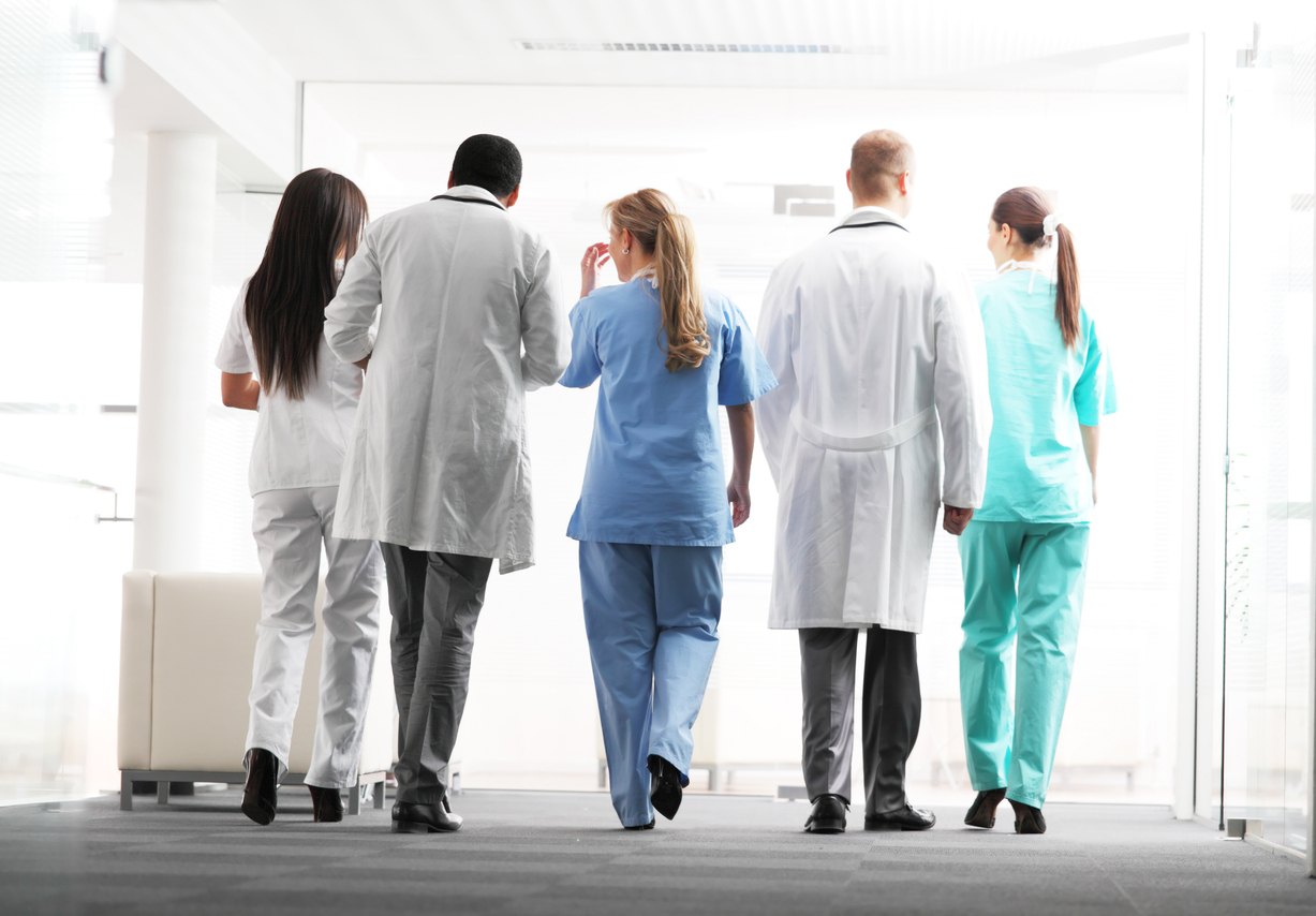 "A large group of hospital teams, doctors and nurses are walking together.  View from behind."