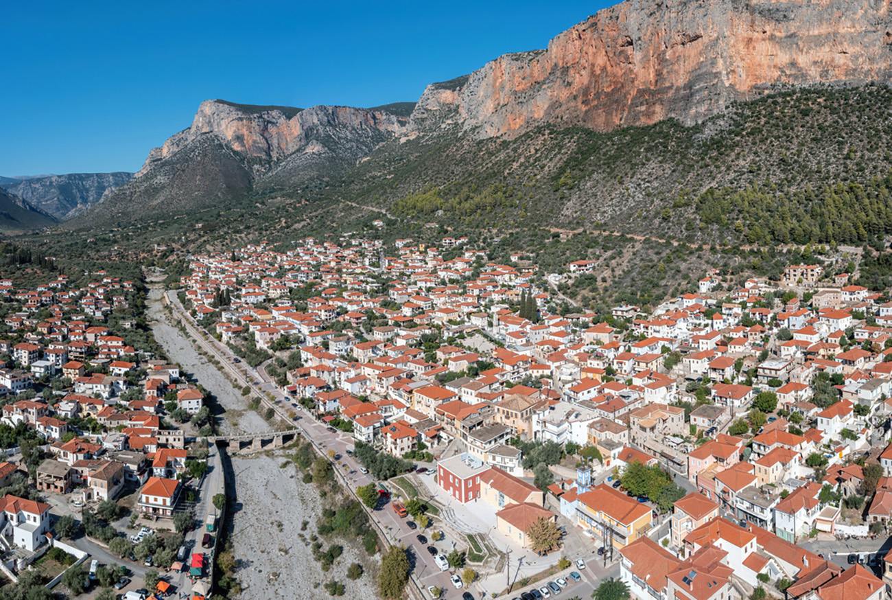 Greece, Leonidio, Arcadia, Peloponnese. Aerial drone view panoramic of town with traditional building, dry Dafnon river bed, bridge, cliff.