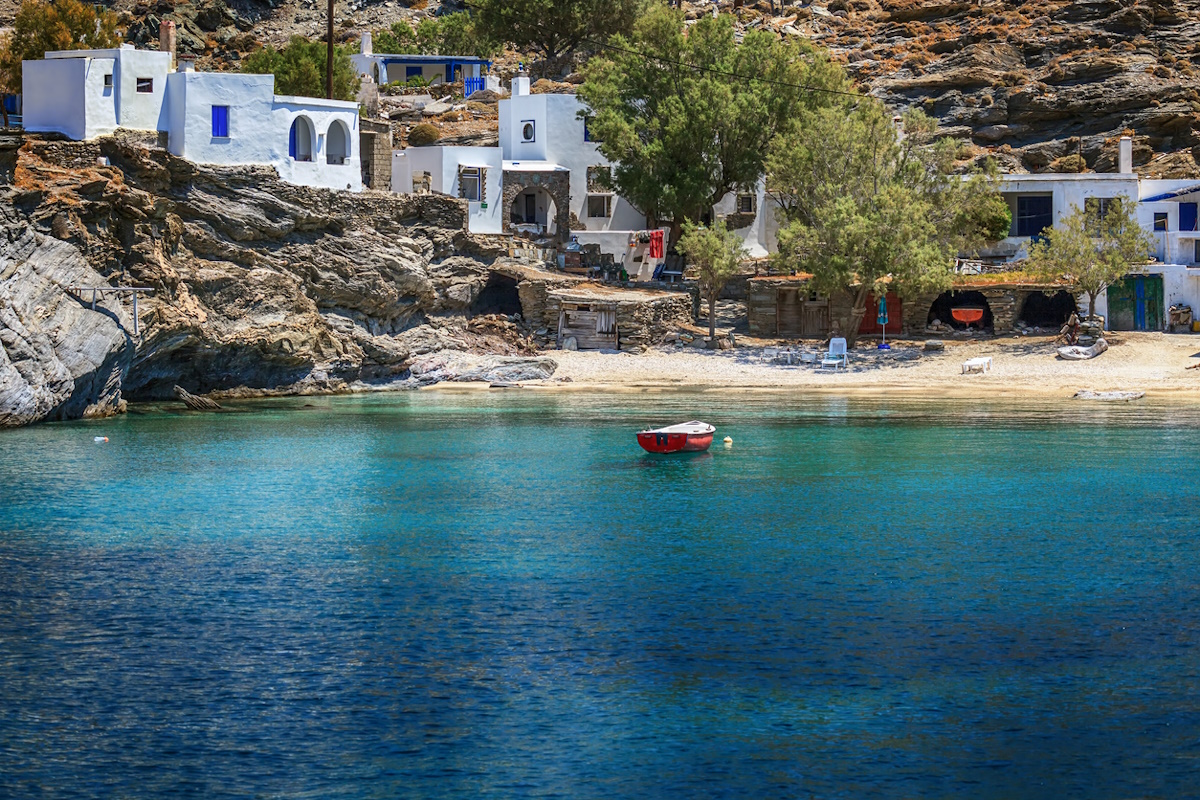 Small village of Mali, in Tinos island, Greece, with clear transparent waters and a fishing boat.